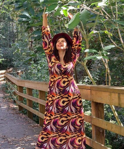 Mulher com vestido comprido em zona arborizada numa ponte de madeira