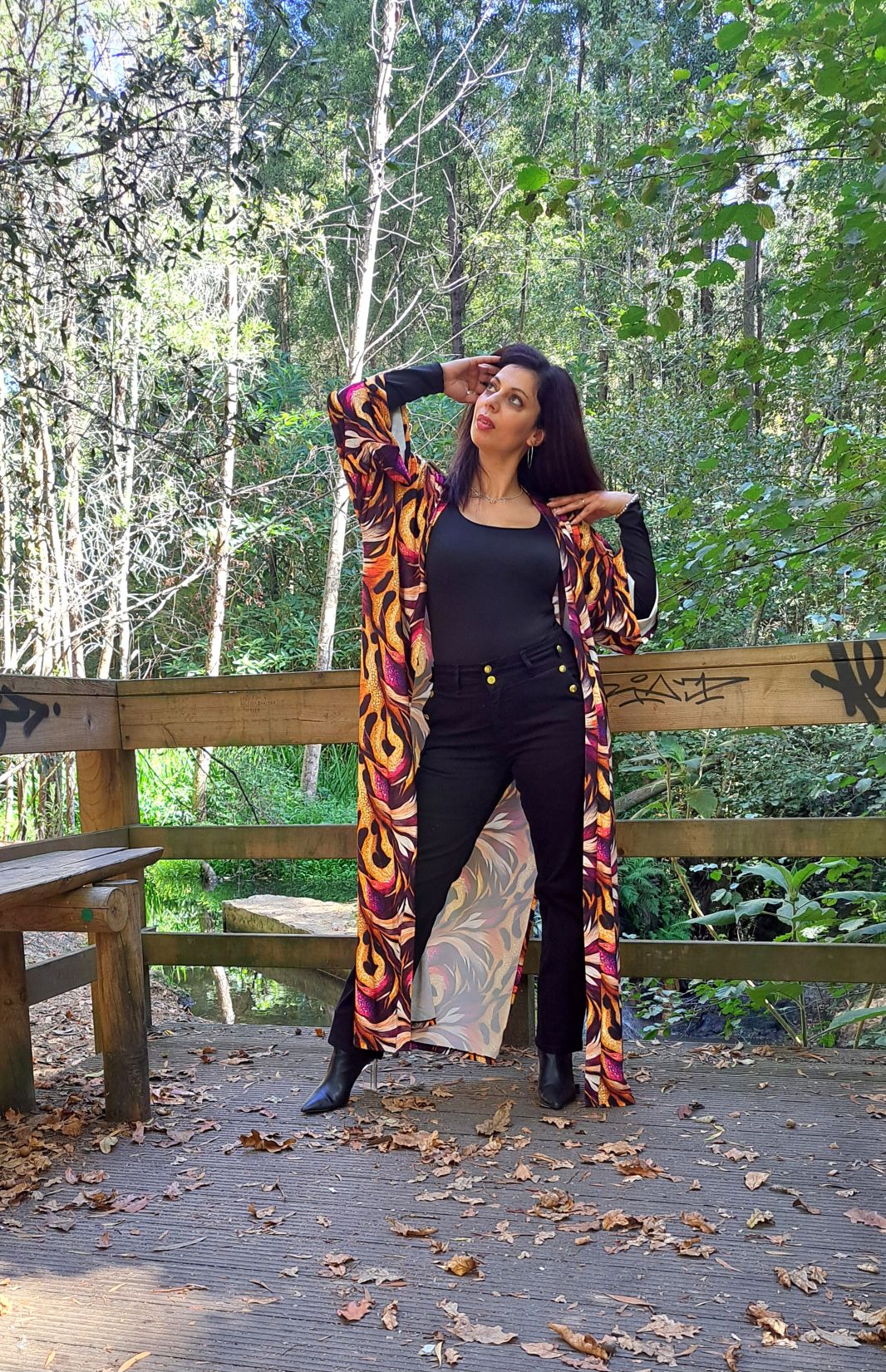 Mulher com roupa preta e um kimono colorido rodeada de árvores