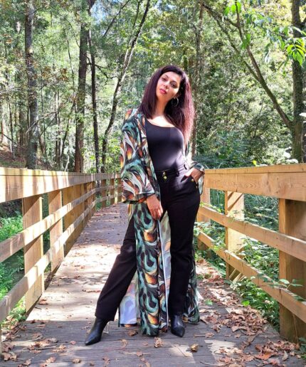 Mulher com roupa preta e um kimono colorido rodeada de árvores