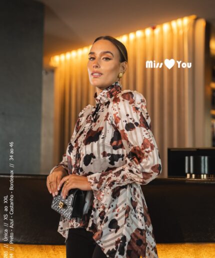 Mulher de cabelo apanhado perto de um balcão luxuoso com uma blusinha estampada da Miss You