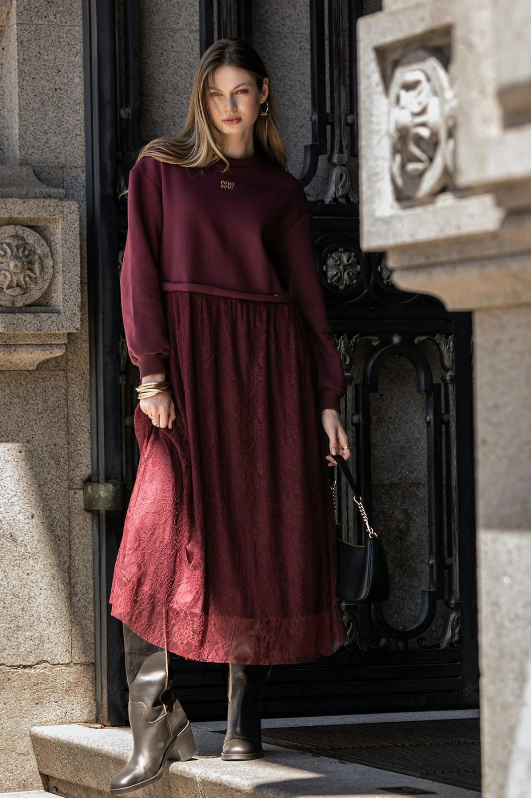 Modelo loira com o vestido bourdeaux da foursoul ao pé de colunas de pedra trabalhadas
